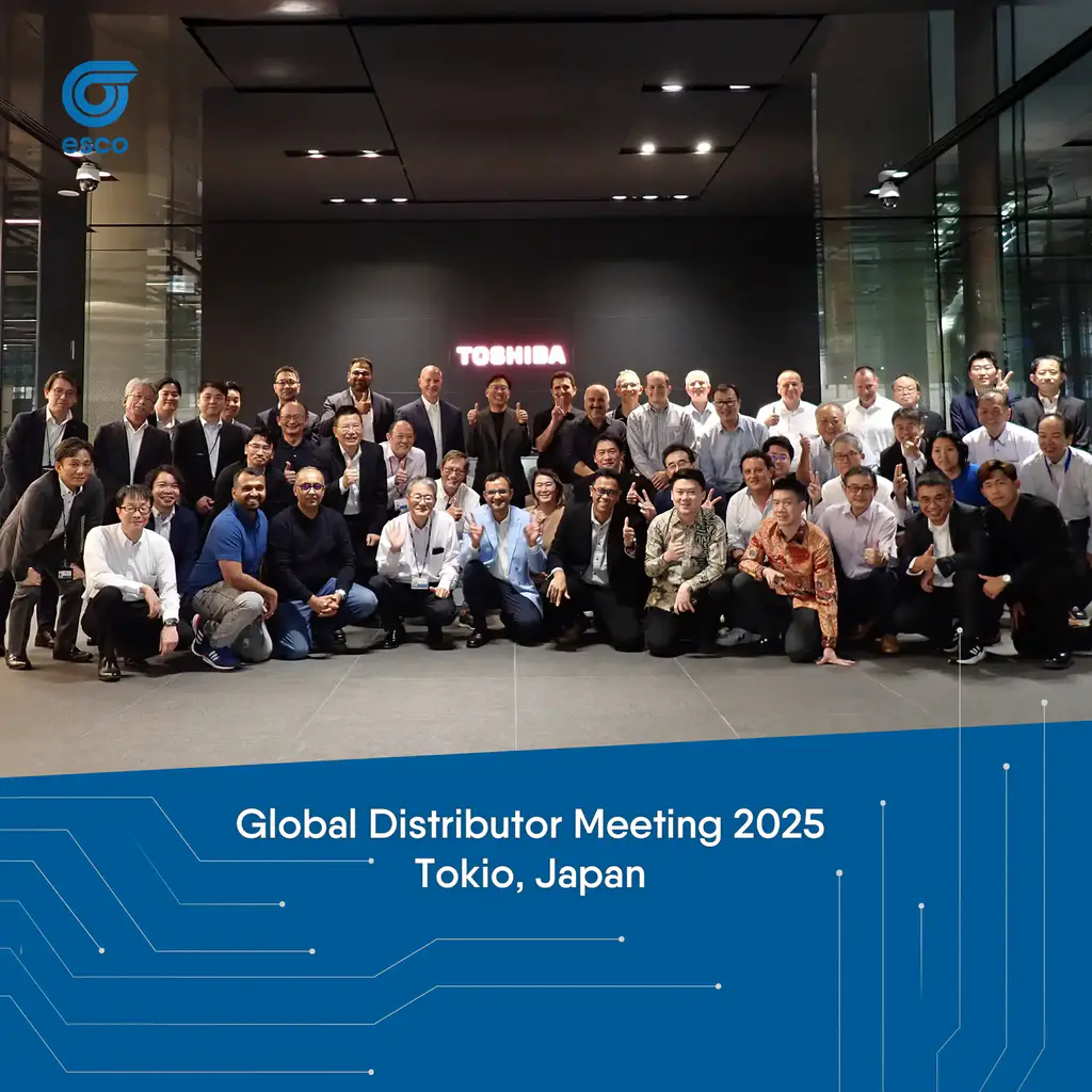 Gruppenfoto aller internationalen Teilnehmer des Toshiba Global Distributor Meeting 2025 vor dem Haupteingang des Toshiba Headquarters in Kawasaki, Tokio. Die Teilnehmer stehen und knien lächelnd vor dem leuchtenden Toshiba-Logo.