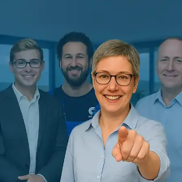 ächelnde ESCO-Mitarbeiterin zeigt direkt in die Kamera – hinter ihr ein gemischtes Team aus Büro und Technik; Signal: Wir suchen dich und laden zu den ESCO-Stellenangeboten ein.